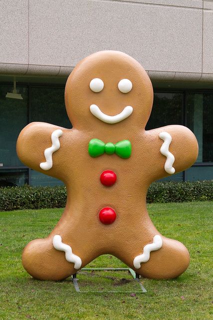 a giant ginger with a green bow tie standing in the grass next to a building