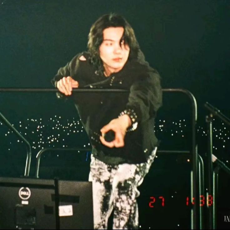 a man standing on top of a stage holding onto a metal bar with his hand