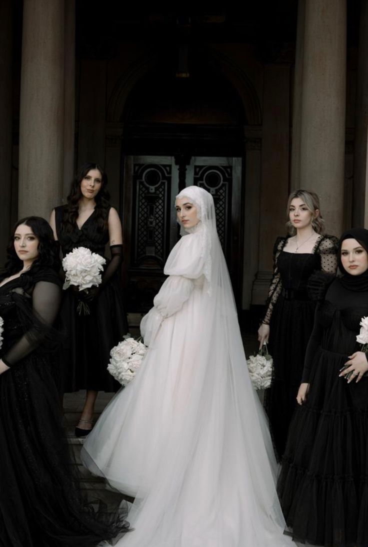 a group of women standing next to each other in dresses and veils on their heads