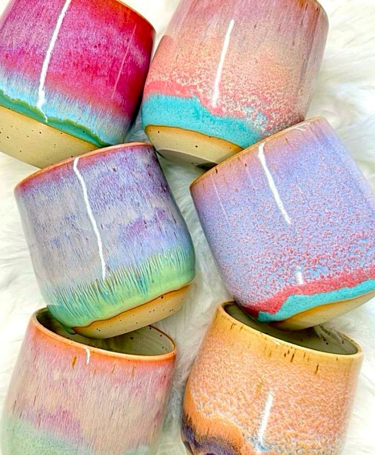 four colorful cups sitting on top of a white furnishing covered floor next to each other