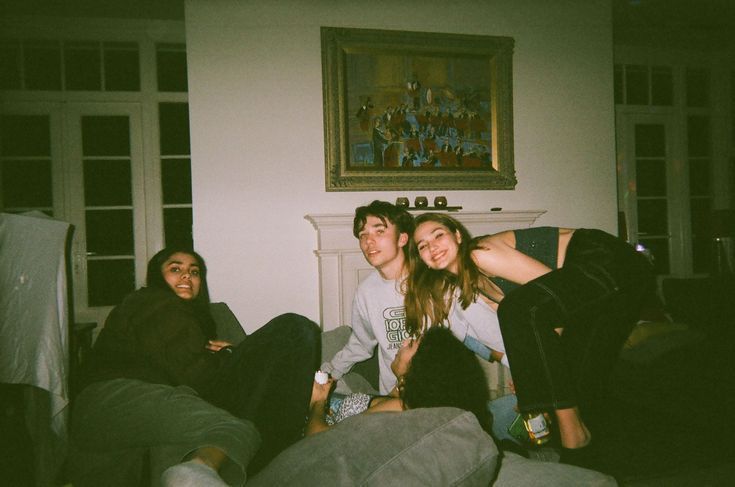 three people are sitting on the floor in front of a fireplace with their arms around each other