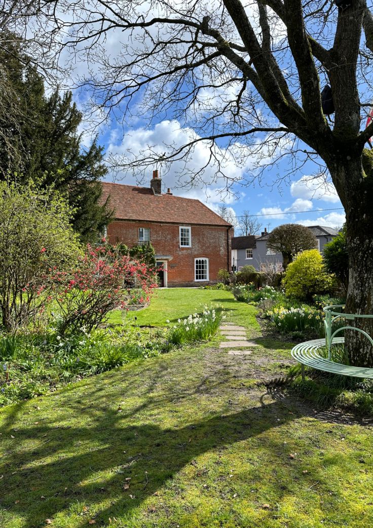 a green bench sitting in the middle of a lush green field next to a tree