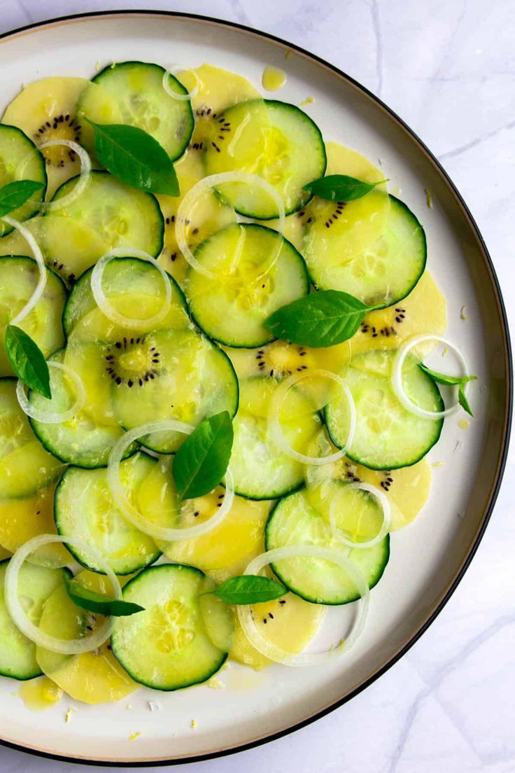 cucumber salad in a white bowl with green leaves