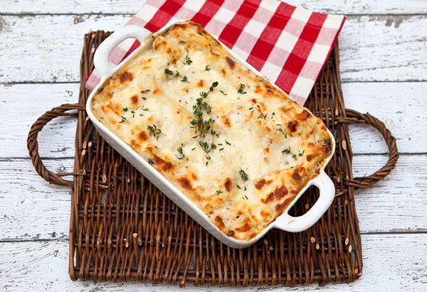 a casserole dish with cheese and parsley on a red and white checkered napkin