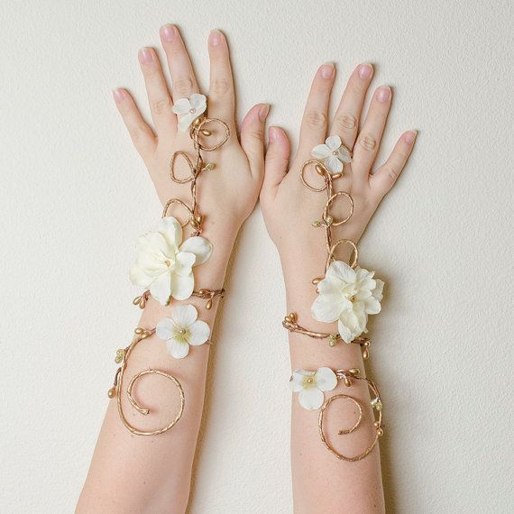 two hands with bracelets and flowers attached to them are shown in front of a white wall