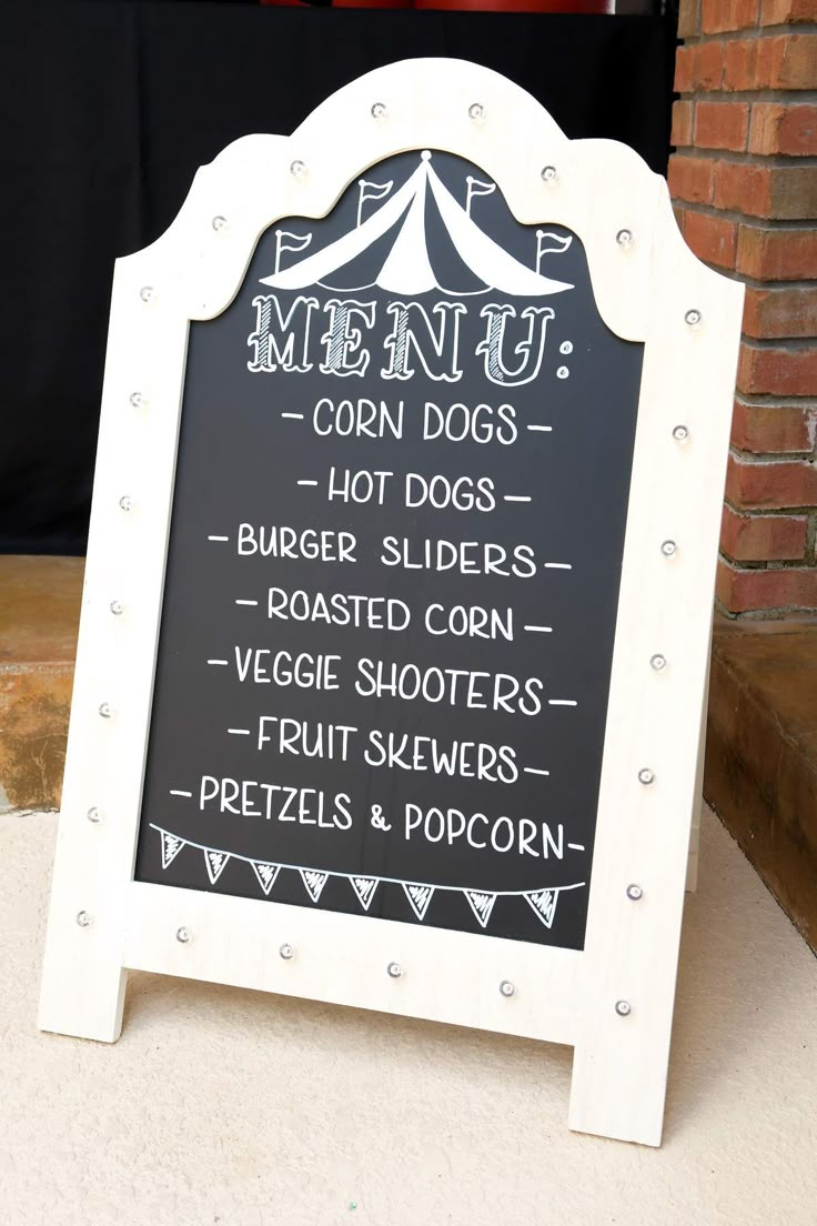 a chalkboard sign with the words menu written on it and an image of a tent in the background