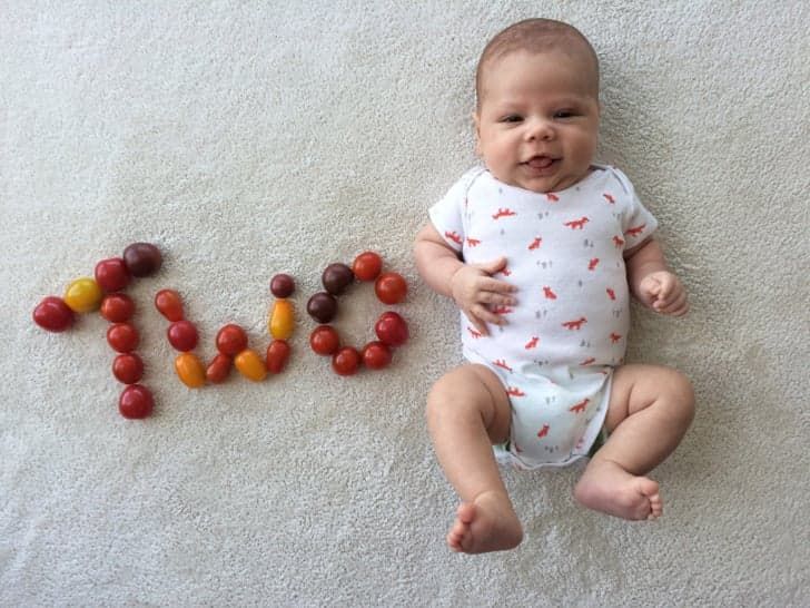 a baby is laying on the floor next to some fruit that spell out word love