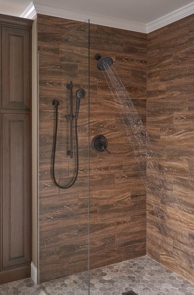 a shower head in the corner of a bathroom with wooden walls and tile flooring