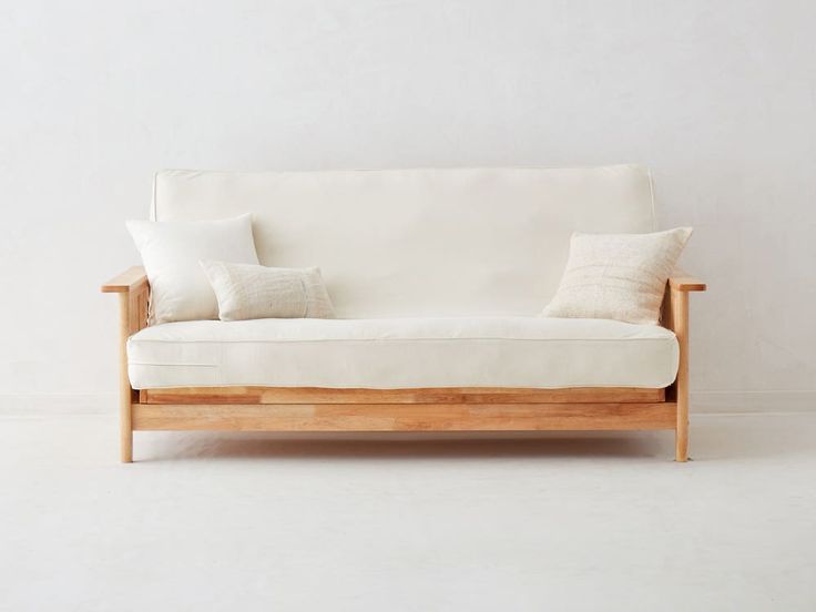 a white couch with two pillows on it's back and one pillow on top