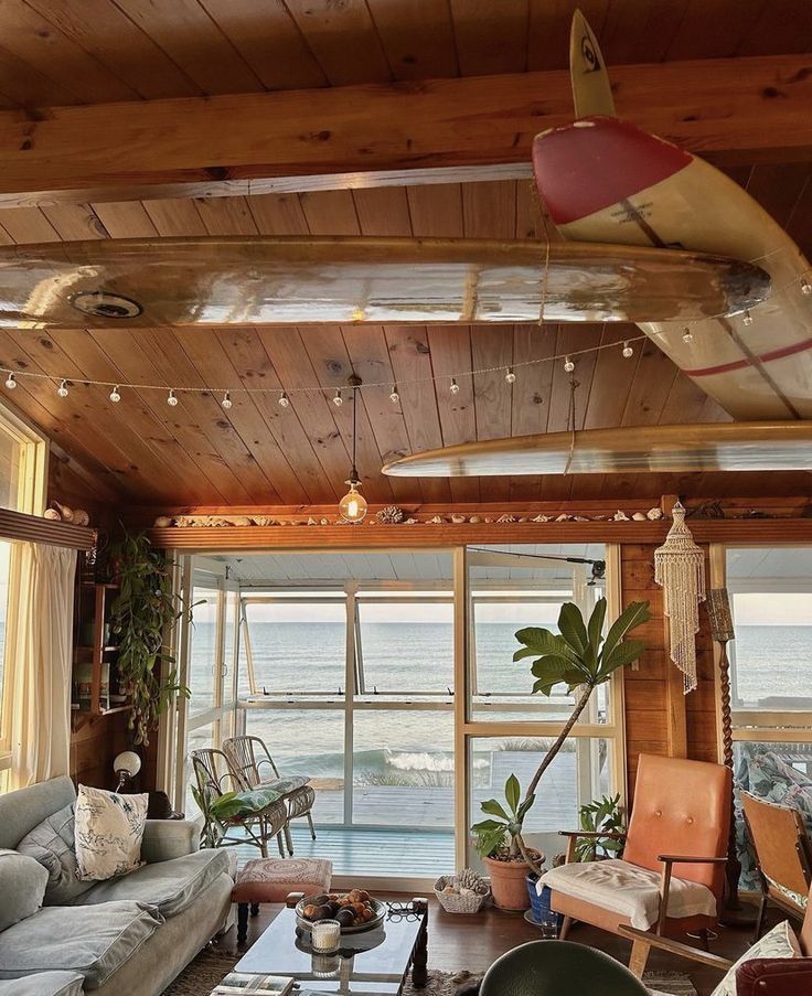 a living room filled with lots of furniture next to a large window overlooking the ocean