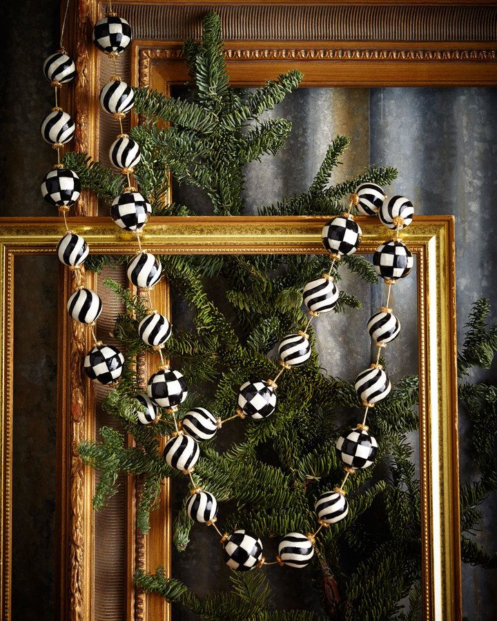 a christmas tree with black and white ornaments hanging from it's branches in front of a gold frame