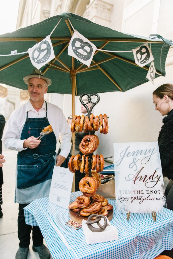 a man standing next to a table with donuts hanging from it's sides