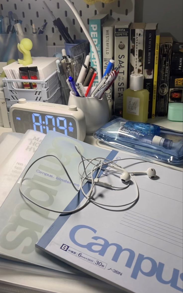 a book with headphones on top of it next to a clock and other office supplies