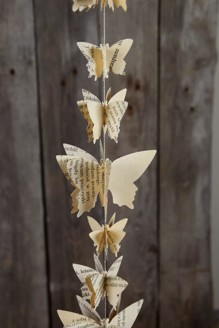 some paper butterflies are hanging from a string on a wooden table with an old book page background