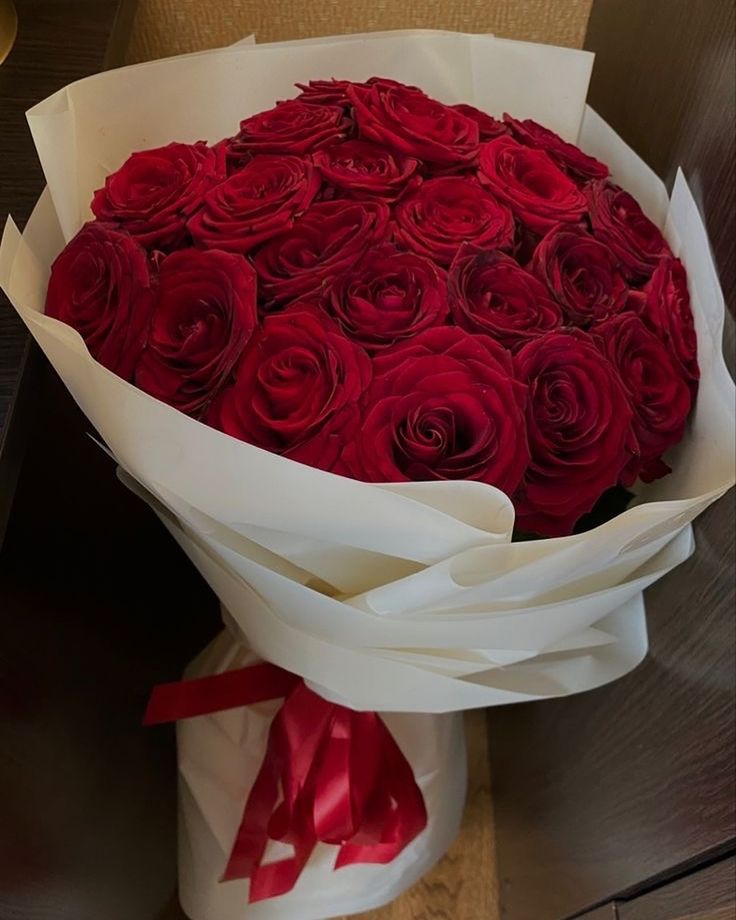 a bouquet of red roses wrapped in white paper