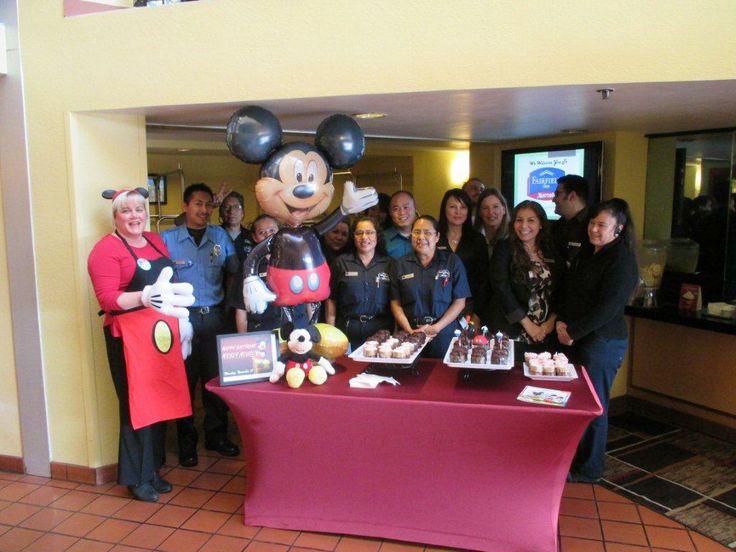 a group of people standing around a table with mickey mouse