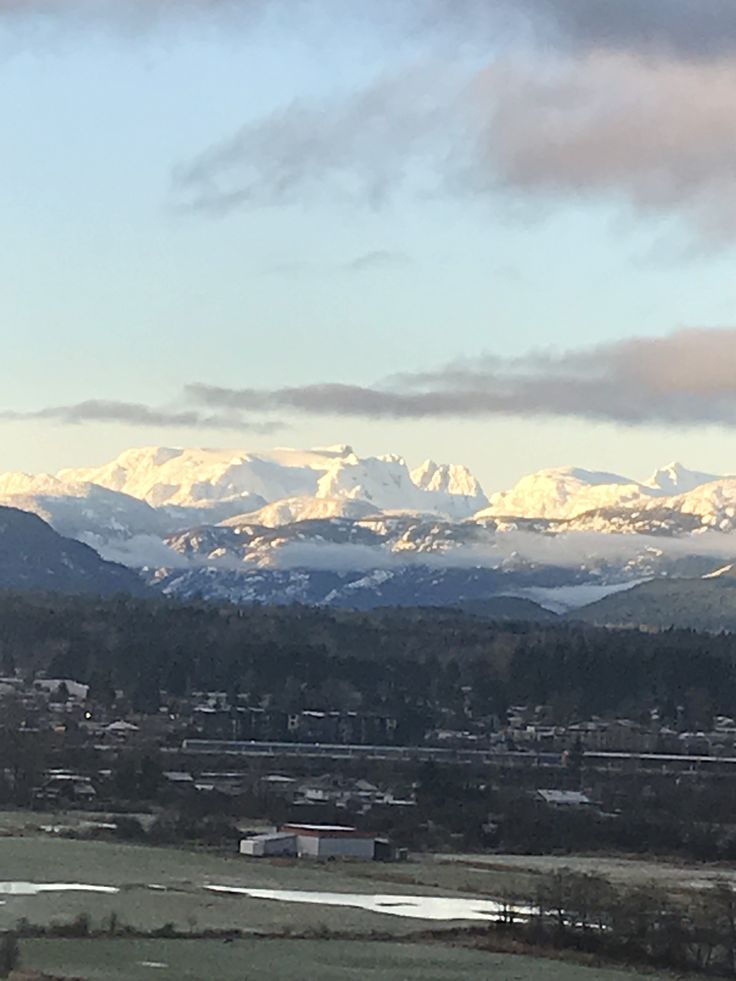 the mountains are covered in snow as seen from an overlook point on a cloudy day