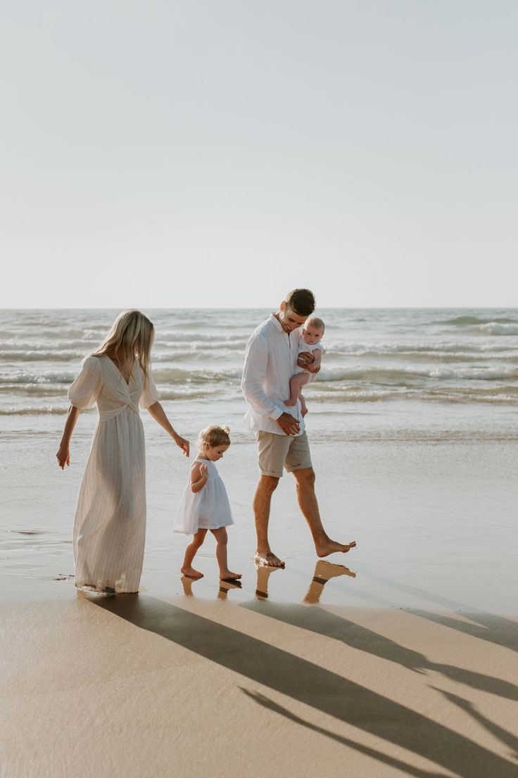 a family walking on the beach holding hands