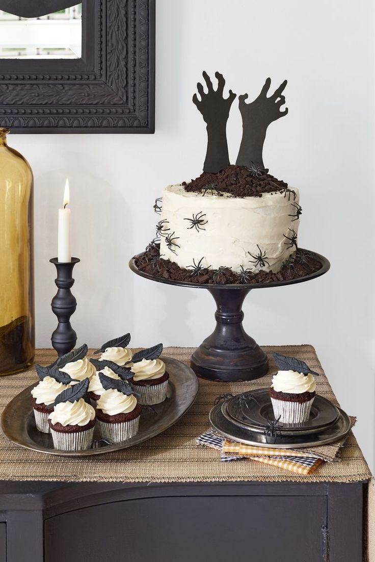 a table topped with cupcakes covered in frosting and spider web decorations on top of it