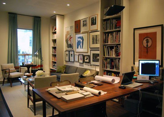 a living room filled with furniture and bookshelves next to a computer monitor on top of a wooden table