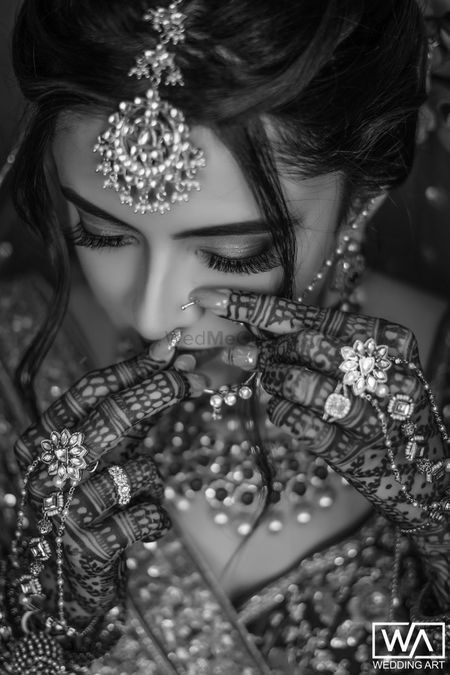 a woman in a bridal outfit with jewelry on her head and hands to her face