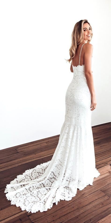 a woman in a white wedding dress standing on a wooden floor with her back to the camera