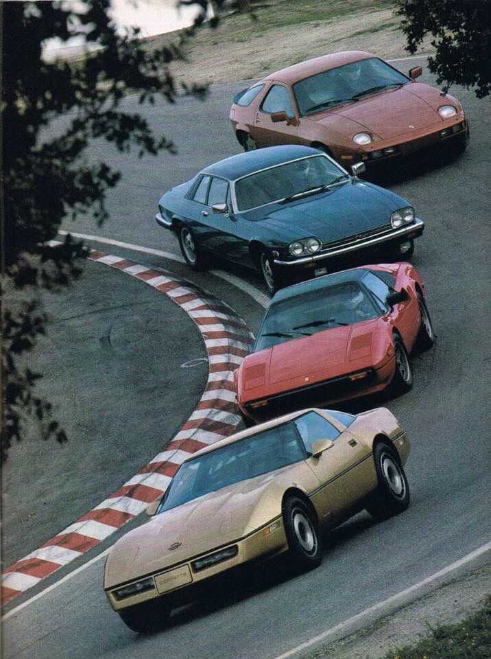 four cars are lined up on the track, one is gold and the other red