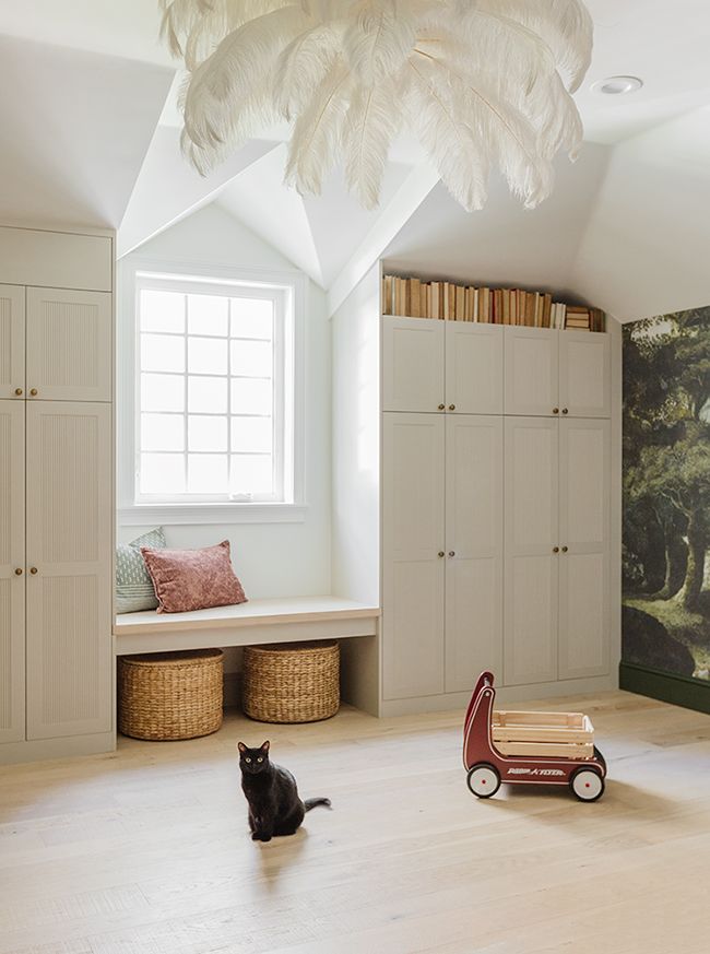 a cat sitting on the floor next to a toy car in a room with white walls