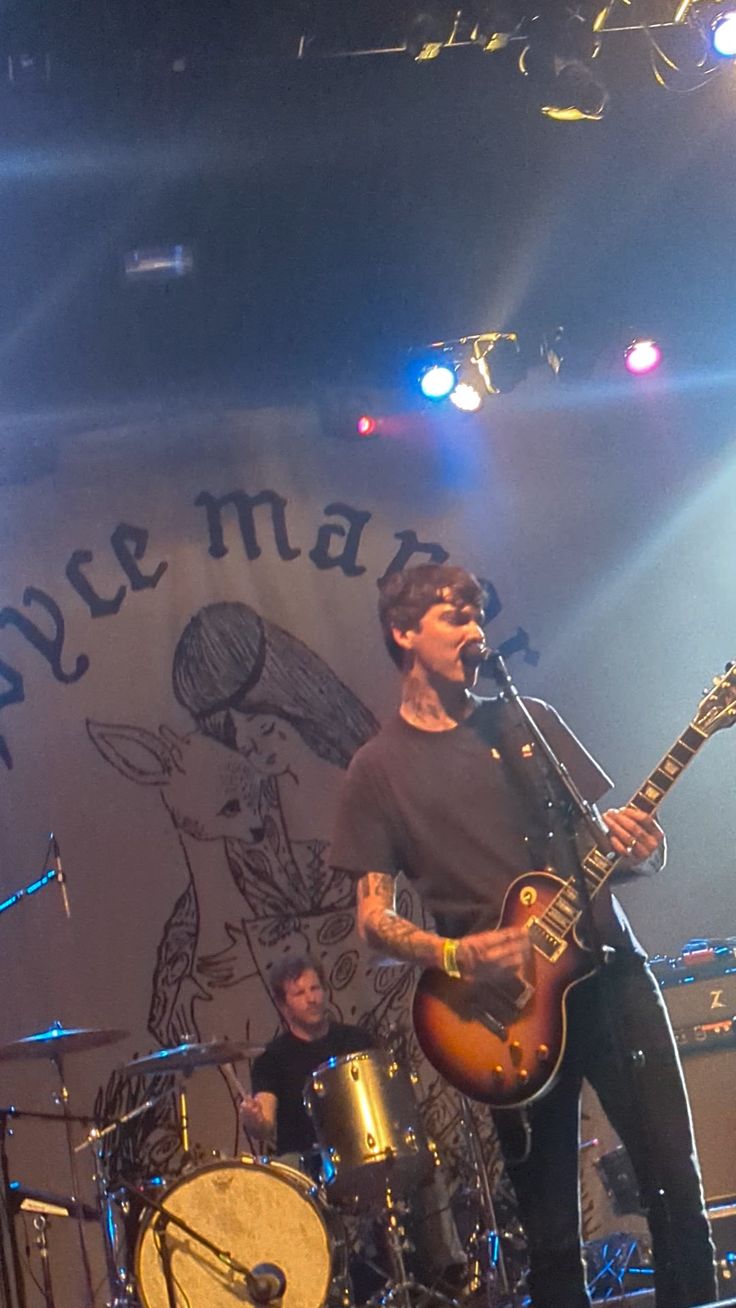 two men on stage with guitars and drums