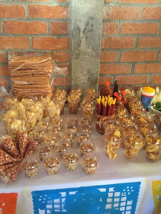 a table topped with lots of different types of snacks and condiments next to a brick wall