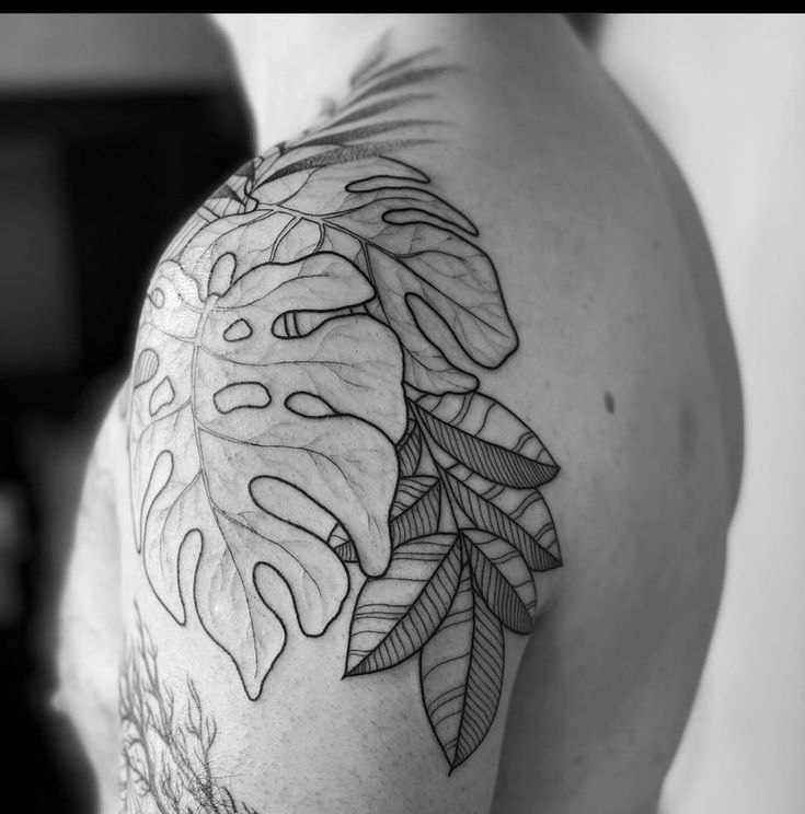 a black and white photo of a man's shoulder with leaves on it