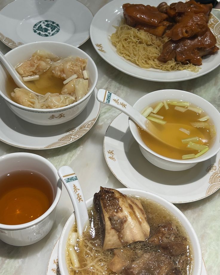 several bowls of food on a table with chopsticks and soup in the middle