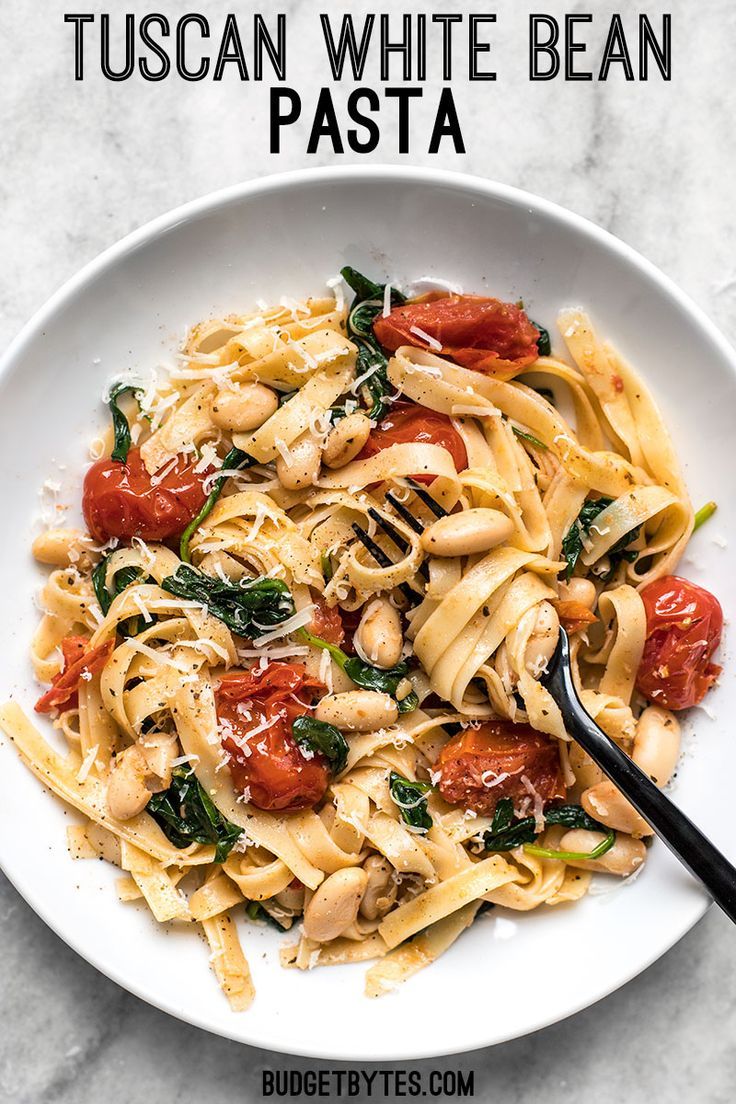 a white bowl filled with pasta and spinach