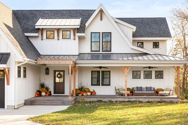 a large white house with black roof and two car garages on the front porch