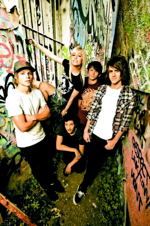 a group of young men standing next to each other in front of graffiti covered walls