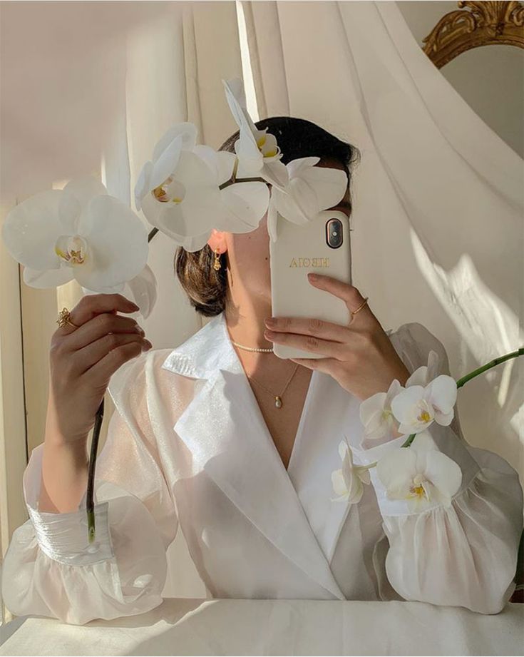 a woman is taking a selfie with her phone and flowers in front of her