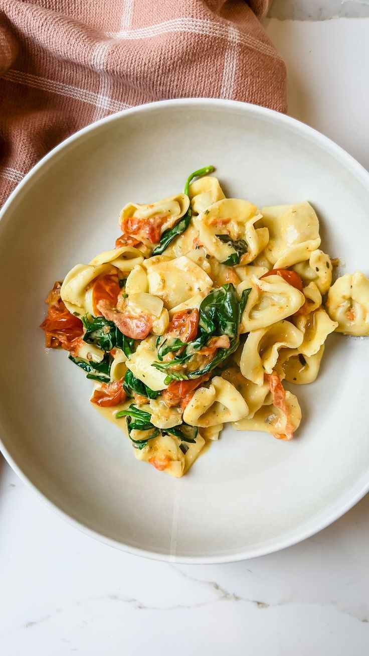 a white plate topped with pasta and spinach