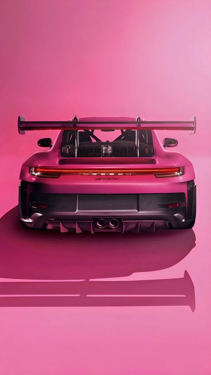 the back end of a pink sports car with its hood up and two skis on it's roof