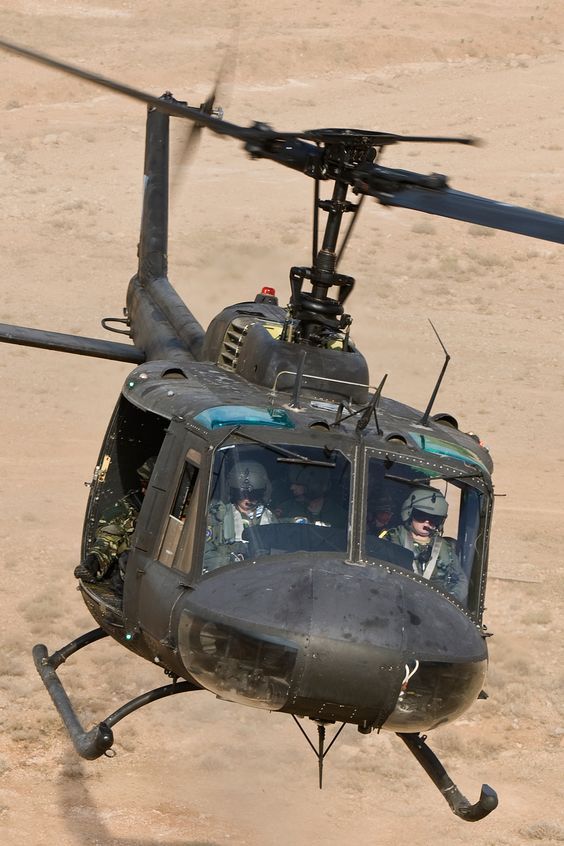 a black helicopter flying through the air with people in it's cockpit and onlookers