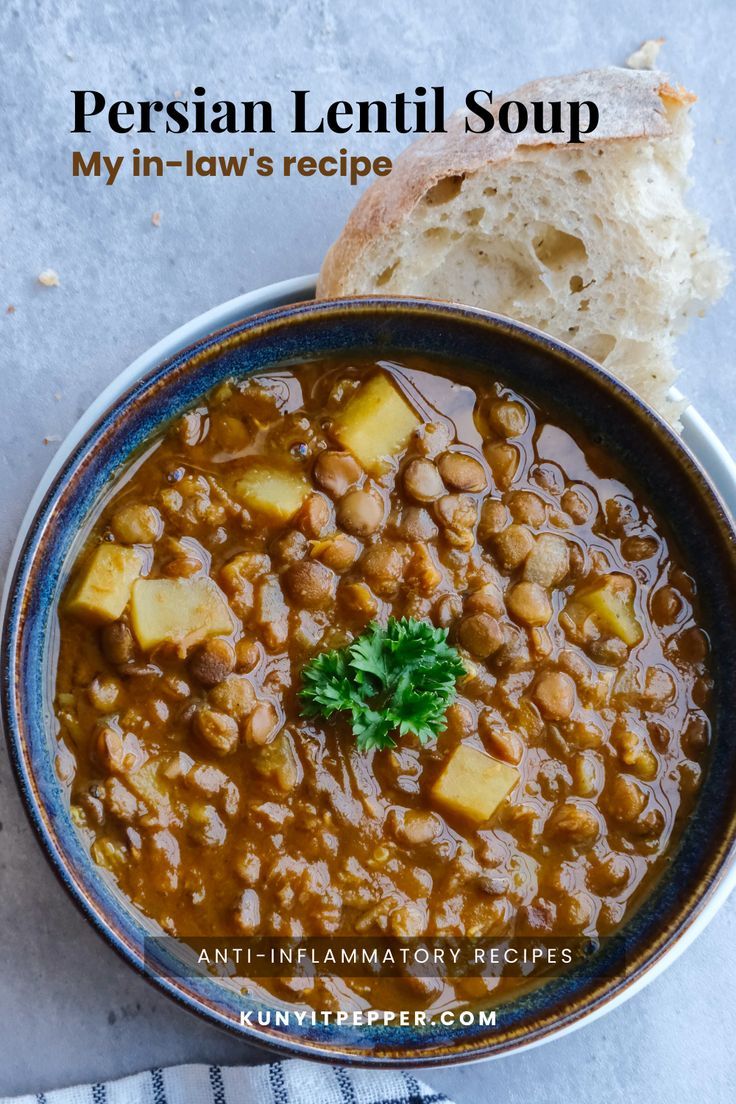 a bowl filled with lentil soup next to a piece of bread on top of a table