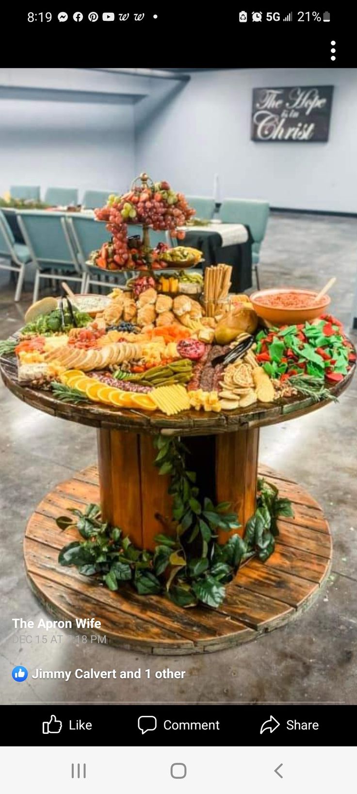 a table full of food on top of a wooden stand with chairs in the background