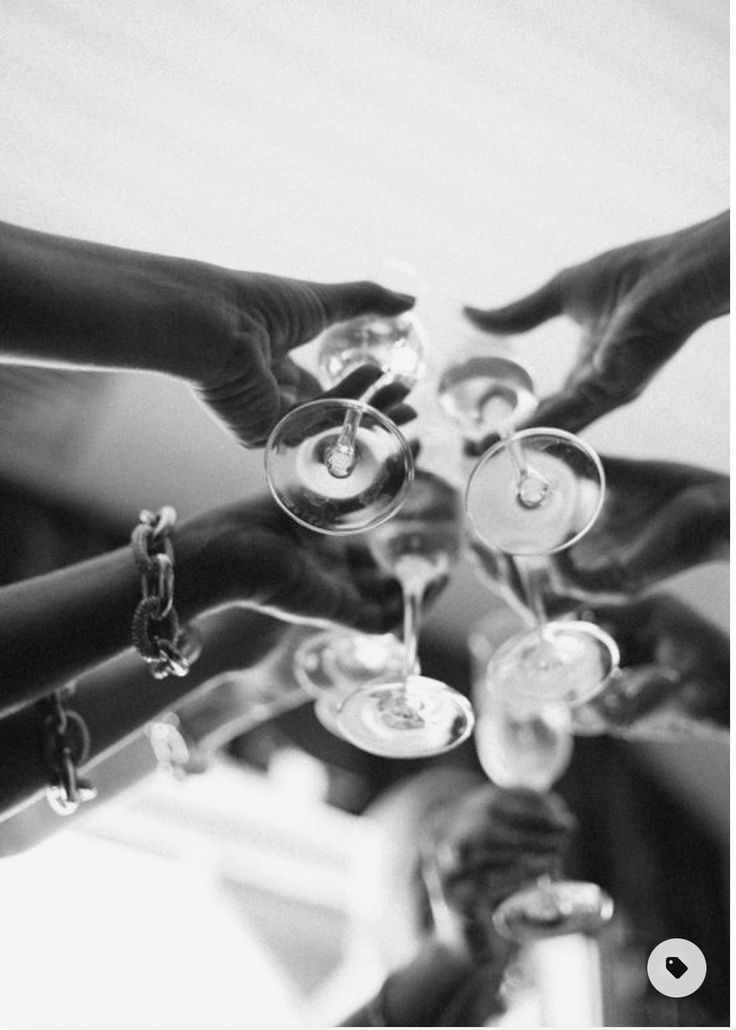 black and white photograph of people holding wine glasses in each other's hands together