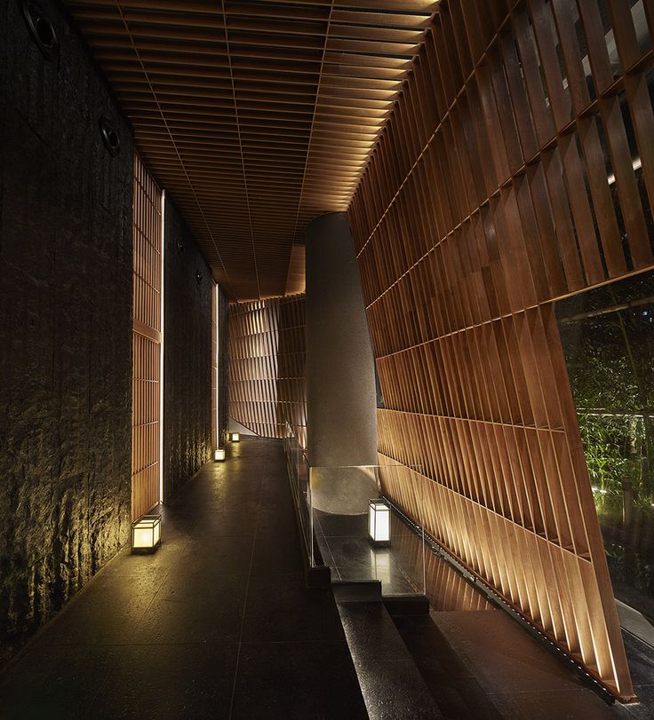 the hallway is lined with wooden slats and lit up by lanterns on either side