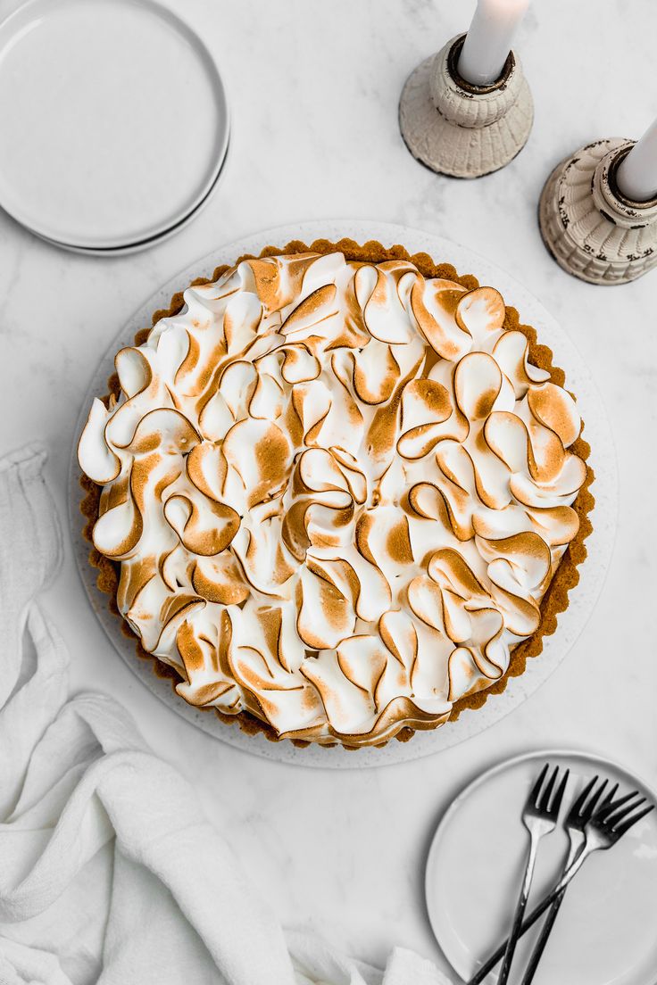 a pie with meringue on top sitting on a table next to silverware