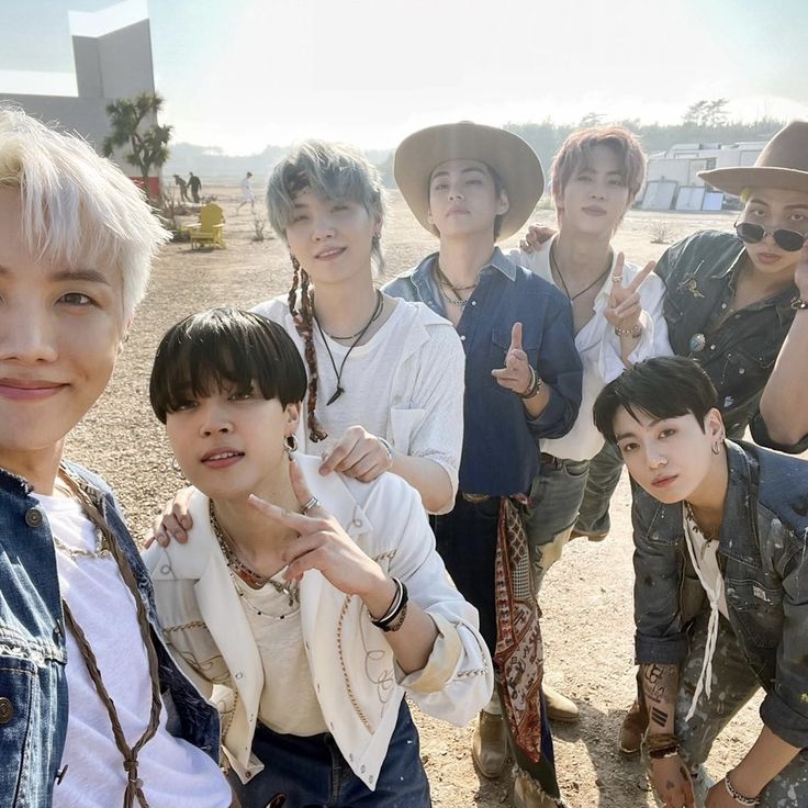 a group of young men standing next to each other on top of a dirt field