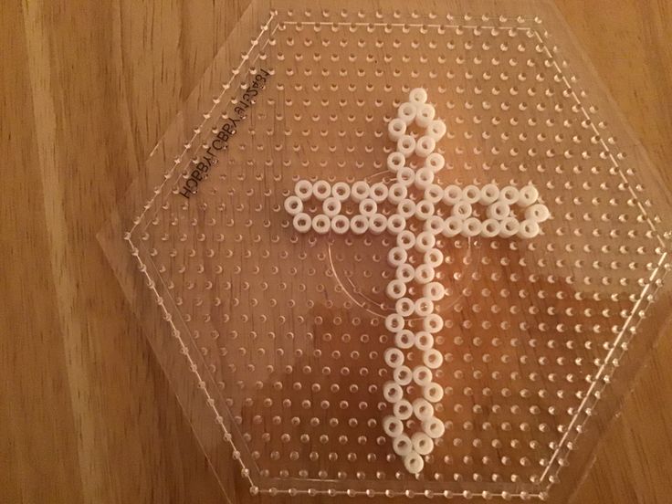 a cross made out of beads sitting on top of a wooden table