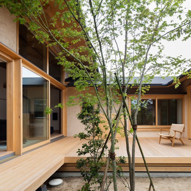 a wooden deck with chairs and trees in the foreground, next to an outdoor dining area