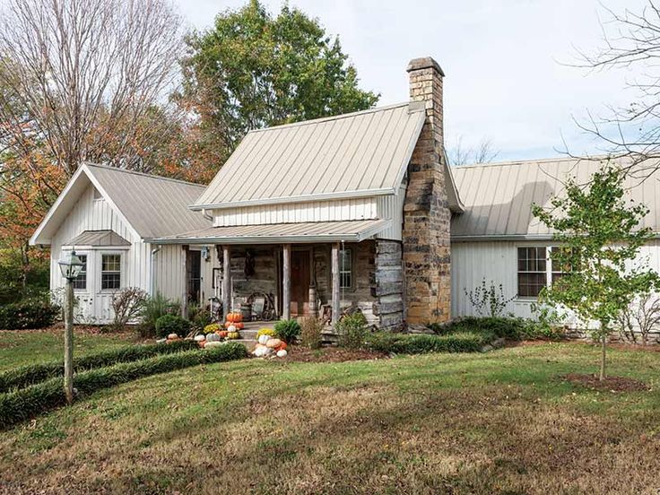 a white house with a metal roof and stone chimney