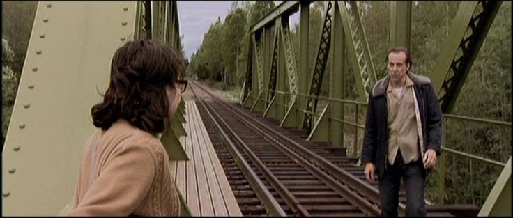 two people are standing on a bridge looking at each other