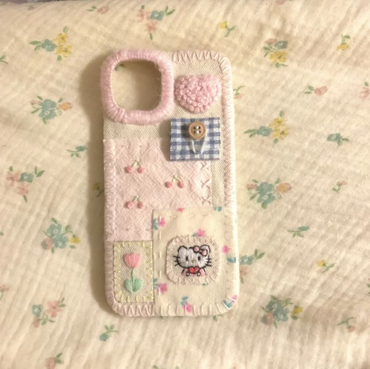 a hello kitty cell phone case is laying on a floral print sheet with a button